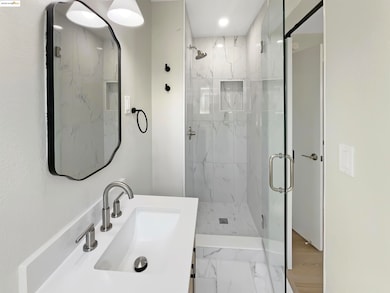Bathroom featuring marble look tiles, a marble finish shower, and vanity