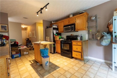 Kitchen with appliances with stainless steel finishes, rail lighting, a textured ceiling, a kitchen island, and light countertops