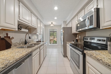 Bright galley kitchen with granite countertops, stainless steel appliances, and abundant cabinet storage. Natural light from dual windows at the end creates the perfect spot for a bistro table or breakfast nook.