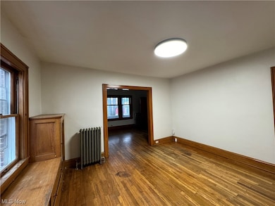 Empty room with dark wood-type flooring, a healthy amount of sunlight, and radiator heating unit