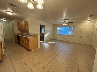 Kitchen with a textured ceiling, light tile patterned floors, freestanding refrigerator, a chandelier, and dishwasher