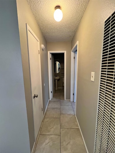 Hallway with light tile patterned flooring, a tex
