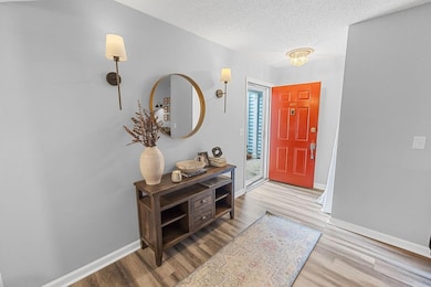Foyer featuring wood finished floors, a textured ceiling, and baseboards