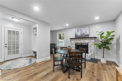 View of the dining area featuring the wood burning fireplace, sitting area, and flow to the mudroom with white storage built-ins