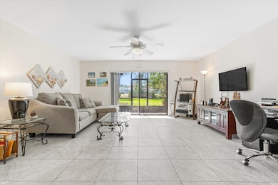 Living room featuring an office area, light tile patterned floors, and ceiling fan