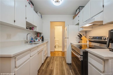Kitchen featuring exhaust hood, white cabinets, light hardwood flooring, electric stove, and sink