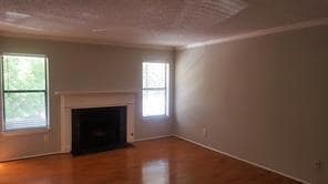 Unfurnished living room with a fireplace, wood finished floors, and ornamental molding