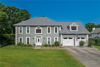 Colonial inspired home with concrete driveway, a front yard, a shingled roof, and stucco siding