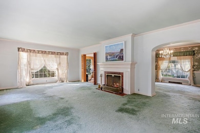 Unfurnished living room featuring ornamental molding, carpet, a brick fireplace, arched walkways, and a chandelier