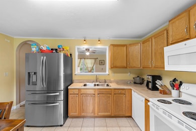 Kitchen featuring white appliances, light tile patterned floors, light countertops, track lighting, and ceiling fan