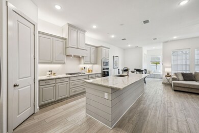 Kitchen featuring tasteful backsplash, open floor plan, light stone countertops, a kitchen island with sink, and recessed lighting