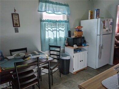Kitchen with white refrigerator, white cabinets, and tile floors
