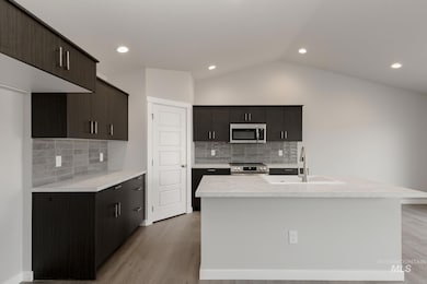 Kitchen with tasteful backsplash, stainless steel appliances, light wood finished floors, a center island with sink, and recessed lighting