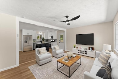 Virtually staged Living area with wood finished floors, and ceiling fan