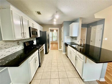 Kitchen featuring a peninsula, white cabinets, stainless steel appliances, and a textured ceiling
