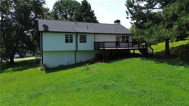 Back of house with stairway, a yard, a deck, and a chimney