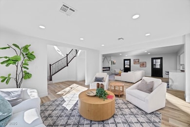 Living room with stairway, light wood-style floors, and recessed lighting