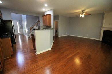 Kitchen featuring brown cabinets, dark wood-type flooring, dark countertops, a fireplace, and recessed lighting