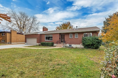 Ranch-style home featuring brick siding, concrete driveway, a chimney, and a front yard