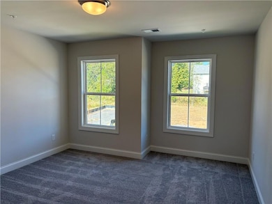 Empty room with dark colored carpet and plenty of natural light
