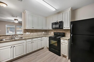 Kitchen with black appliances, white cabinets, and sink