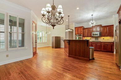 Kitchen with a chandelier, stainless steel appliances, dark countertops, wood finished floors, and ornamental molding