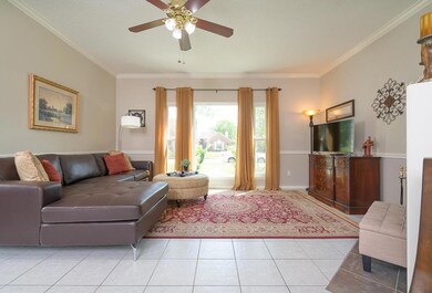 An alternate view of the family room highlights the durable ceramic tile floors, elegant chair rail molding, and abundant natural light streaming in through a trio of double paned plate glass windows dressed with stylish draperies.