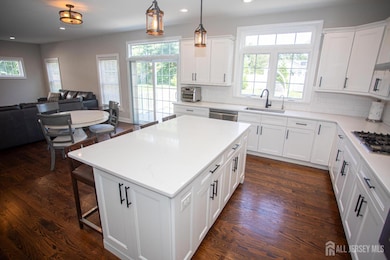 This view highlights the oversized center island—perfect for meal prep, casual dining, or entertaining. Surrounded by sleek stainless steel appliances, a double oven, and designer finishes, this kitchen is as functional as it is beautiful.