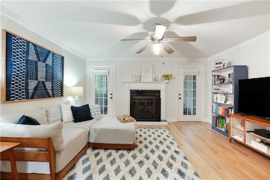 Living area with wood finished floors, a ceiling fan, crown molding, a high end fireplace, and baseboards