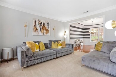 Carpeted living area with ornamental molding and a chandelier
