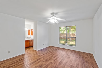 Unfurnished bedroom with wood finished floors, ensuite bathroom, and a ceiling fan
