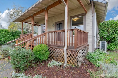 HUGE covered front porch looks out at lovingly curated foliage in fully fenced yard.
