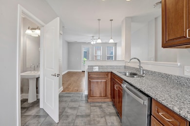 Kitchen with a sink, a ceiling fan, light granite countertops, lots of cabinetry, and ss dishwasher