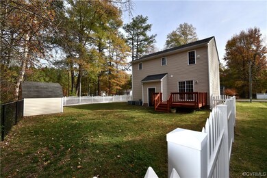 Back of property featuring a storage shed, a yard, and a wooden deck