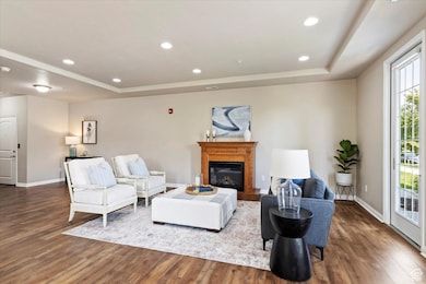 Living room featuring a tray ceiling, recessed lighting, laminate wood finished floors, and a glass covered fireplace