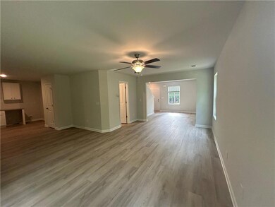 Unfurnished living room featuring baseboards, ceiling fan, and light wood-style flooring