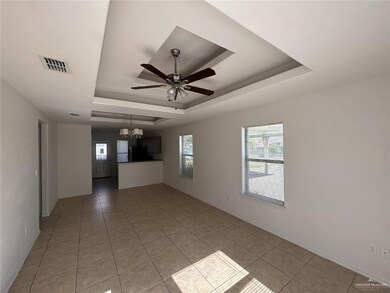 Unfurnished room featuring a raised ceiling, ceiling fan, light tile patterned floors, and a chandelier
