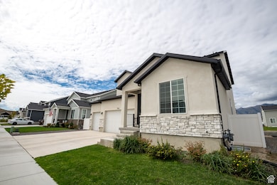 View of front of house featuring stone siding, driveway, stucco siding, a front lawn, and a residential view