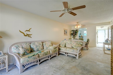 Living room with concrete floors, a textured ceiling, and a ceiling fan