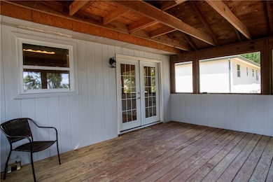 Unfurnished sunroom featuring french doors, plenty of natural light, and beam ceiling