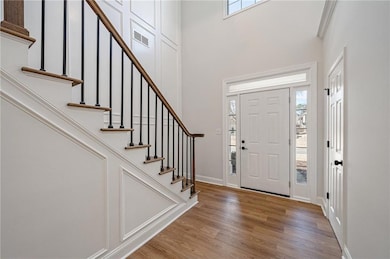 Entryway with plenty of natural light, wood finished floors, a high ceiling, and stairway