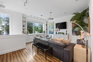 Living area with track lighting, wood finished floors, built in shelves, plenty of natural light, and crown molding