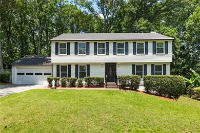 Colonial inspired home with driveway, an attached garage, and a front yard