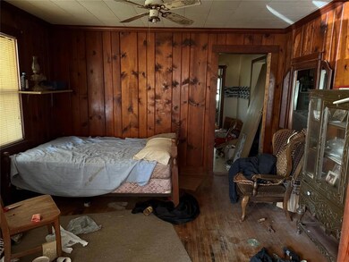 Bedroom with wooden walls, wood finished floors, and a ceiling fan