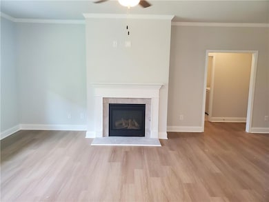 Unfurnished living room featuring ornamental molding, light wood-type flooring, a glass covered fireplace, and ceiling fan