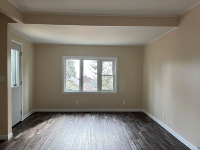Empty room with crown molding, baseboards, dark wood finished floors, and visible vents