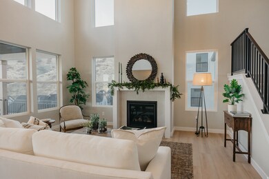 Living room featuring a towering ceiling, wood finished floors, stairs, and a fireplace