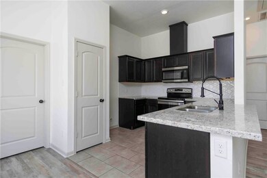 Kitchen with a peninsula, decorative backsplash, stainless steel appliances, light stone countertops, and light tile patterned floors