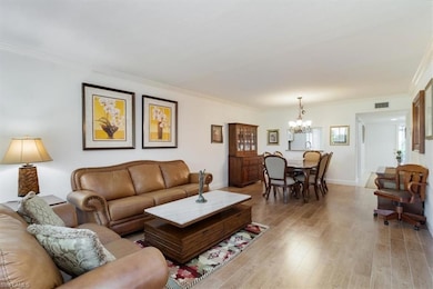 Living room featuring tile  wood-likeflooring, a notable chandelier, and ornamental molding