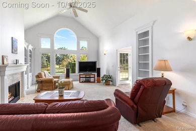 Living room with built in shelves, carpet, high vaulted ceiling, a tile fireplace, and a ceiling fan